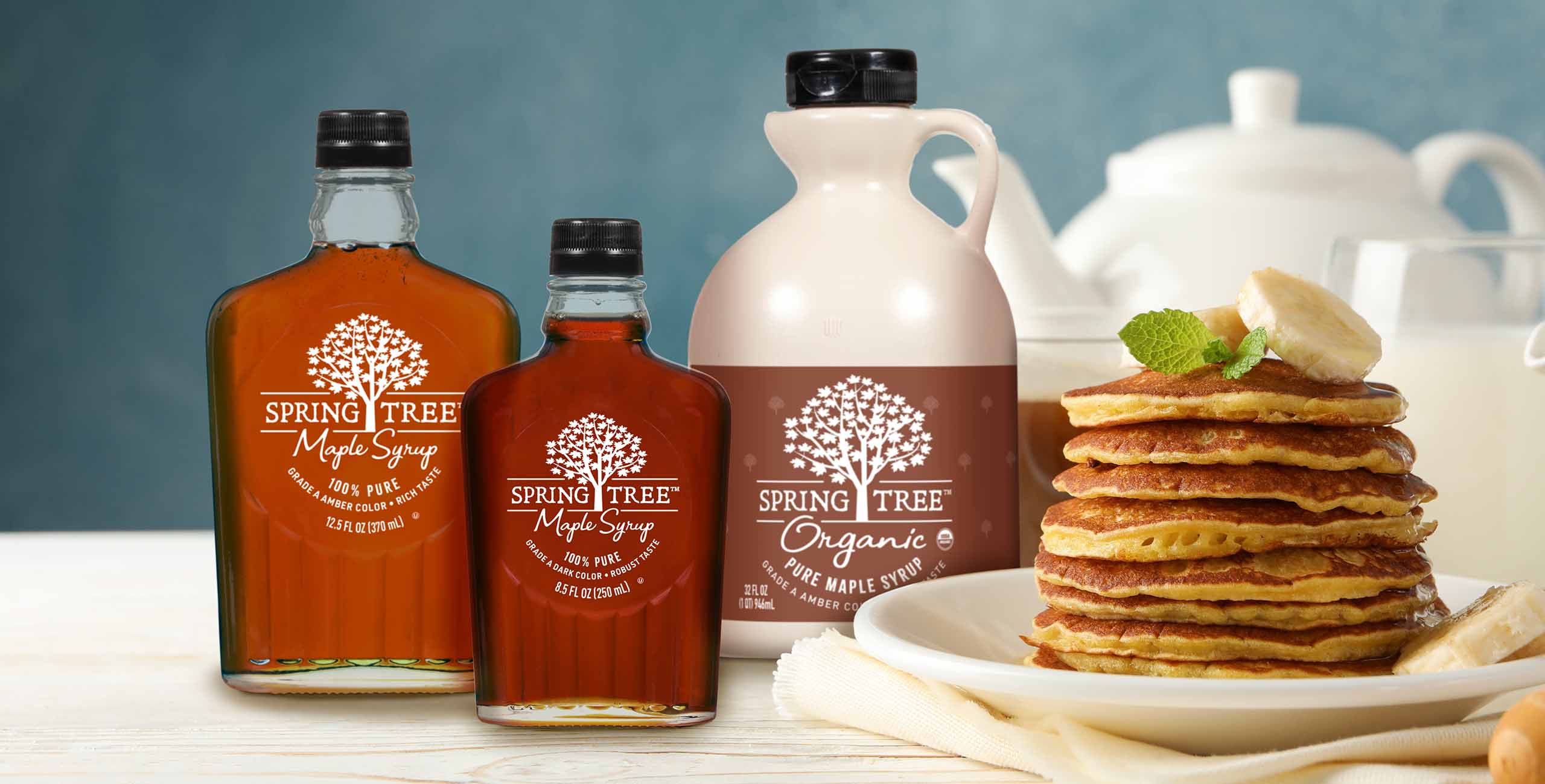 Spring Tree Maple Syrup bottles on table with stack of pancakes